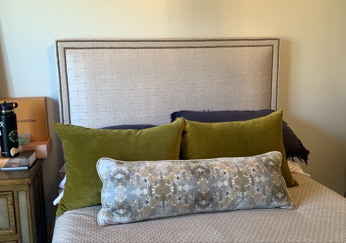 Linen headboard bed with green pillows