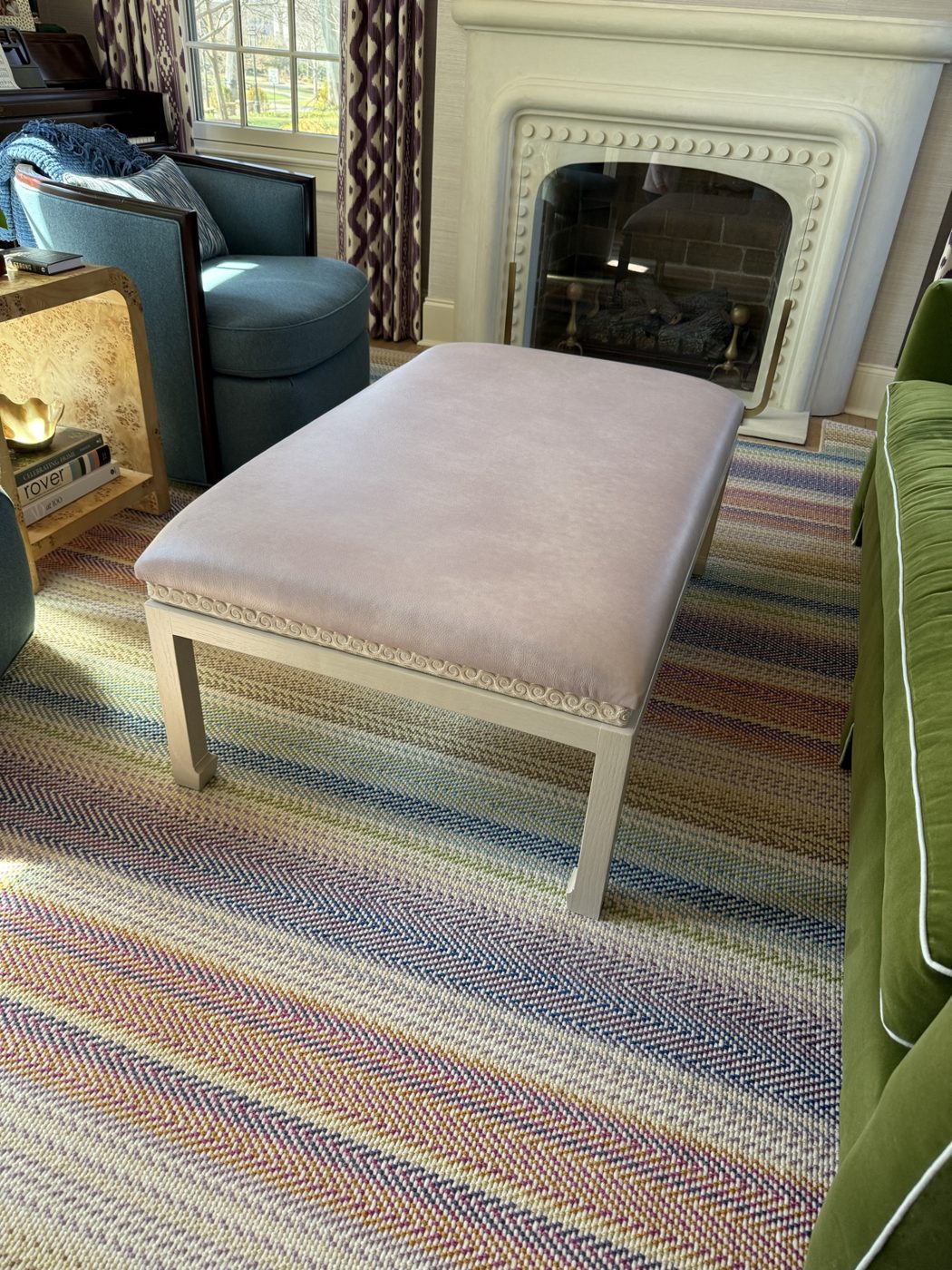 Blush ottoman by fireplace