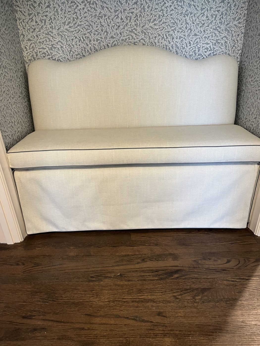 White upholstered bench in wallpapered nook