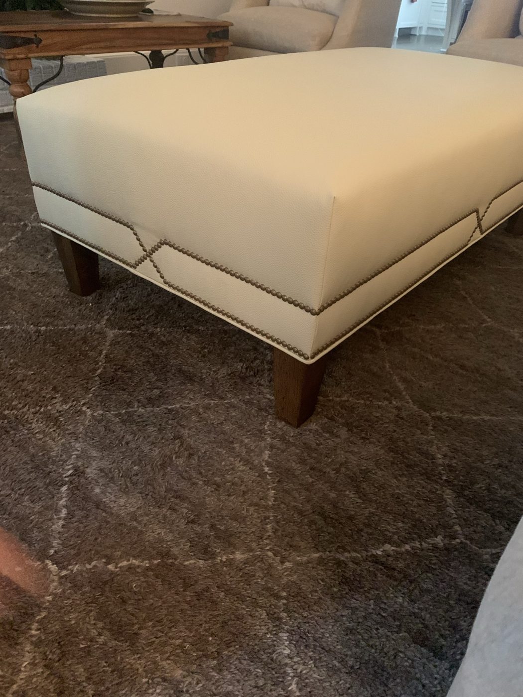 Cream ottoman with Greek-key nailhead trim