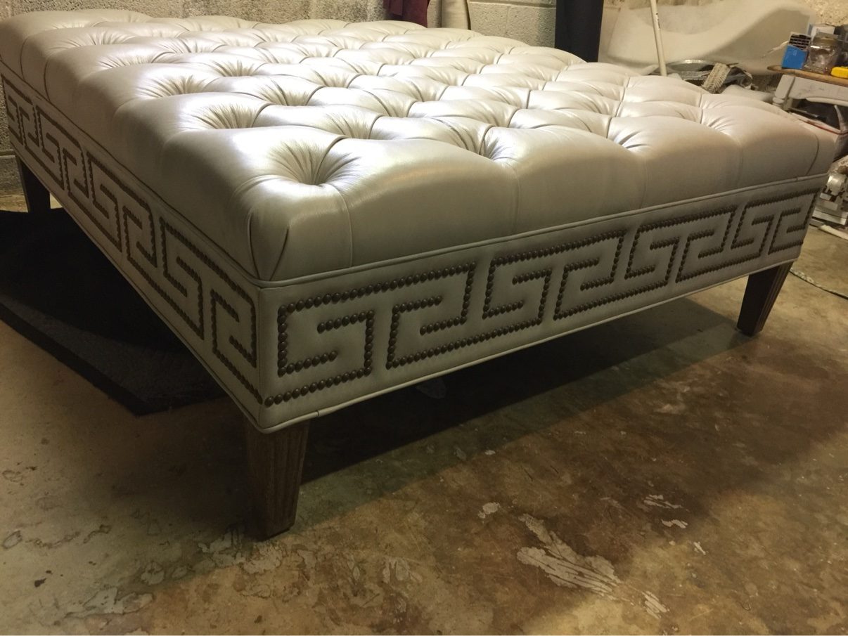Leather tufted ottoman with Greek-key nailhead band