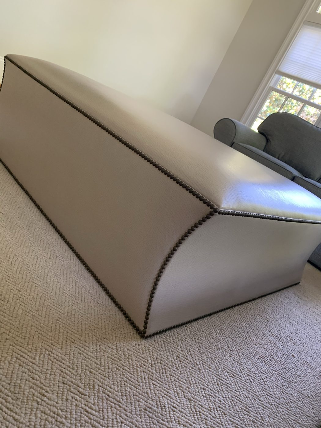 Cream leather ottoman, nailhead detail