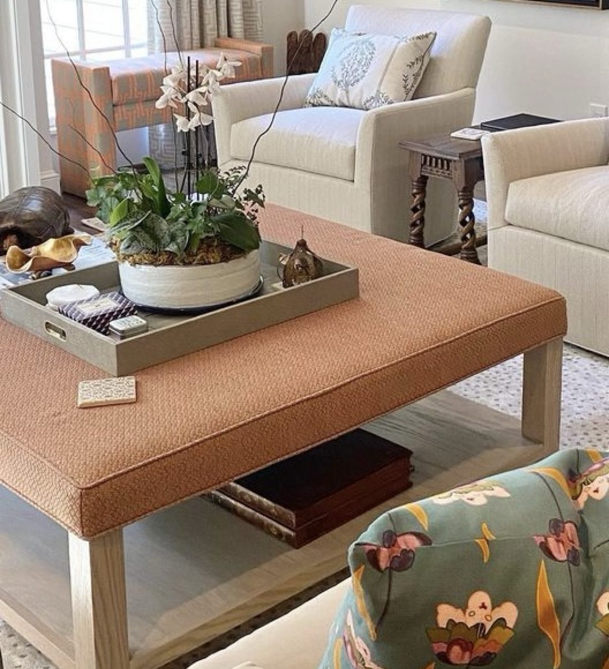 Living room with rust upholstered coffee-table ottoman + cream swivel chairs (tiny black circle artifact at bottom-left corner; crop bottom ~4% if used large)