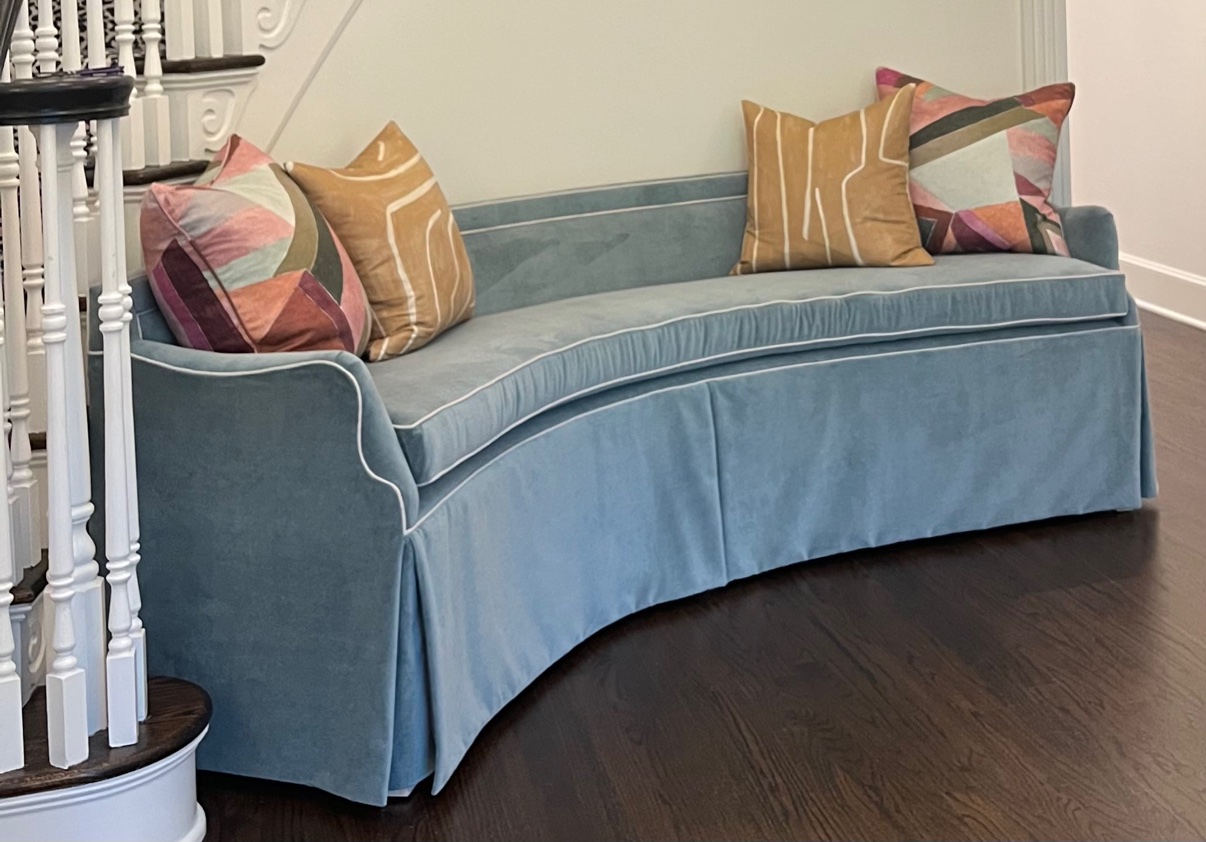 Curved blue velvet banquette with colorful pillows